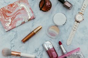 Makeup bag on table with beauty products and sunglasses